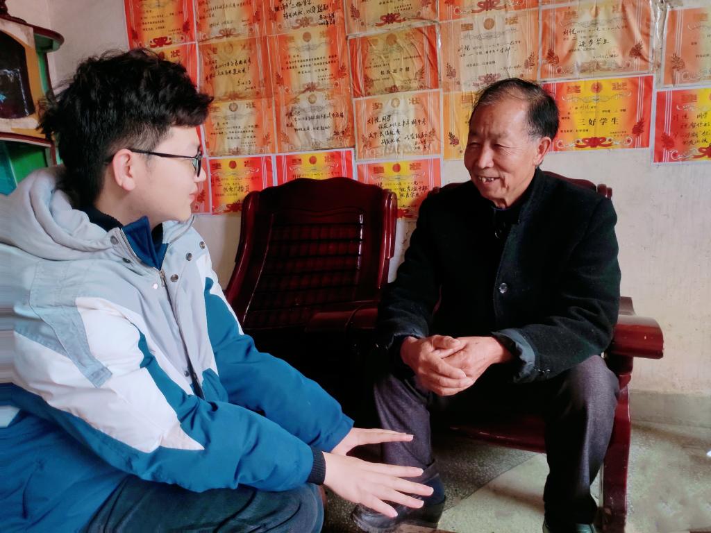 预备党员彭程超同志在聆听舅爷分享家乡的红色故事