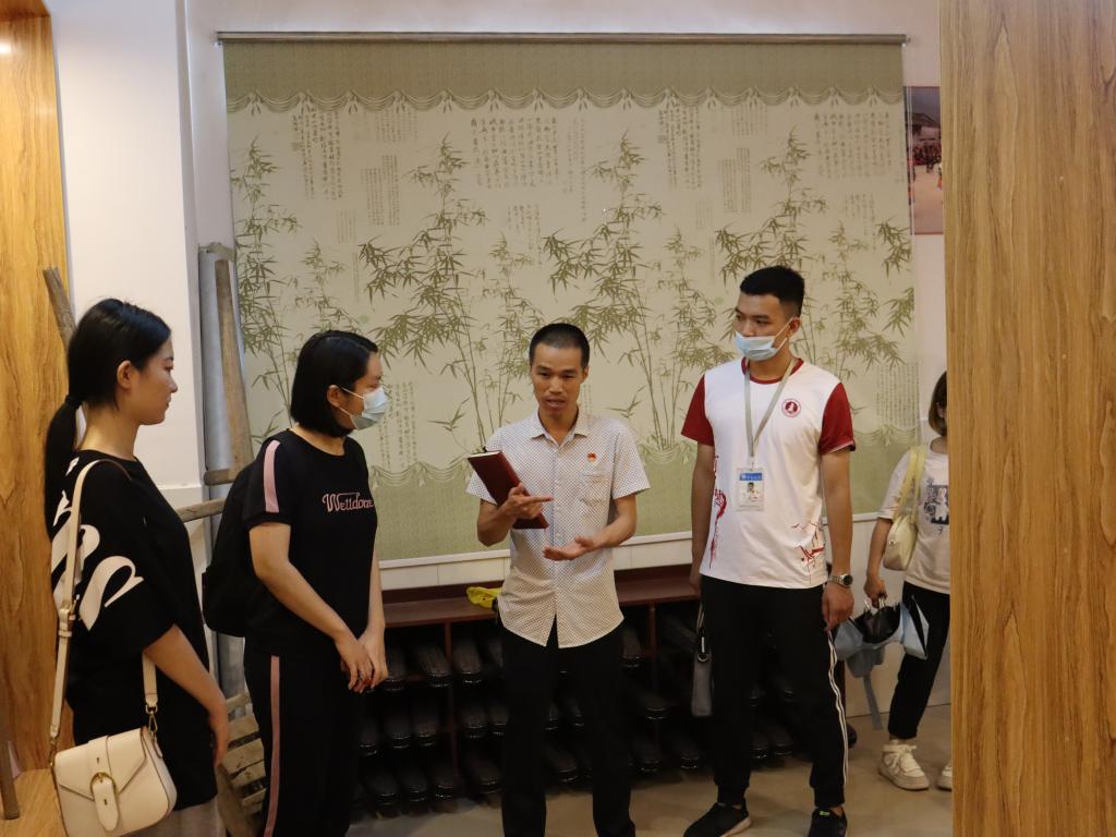 图为两安瑶族乡中心小学董事长潘新庭(左三)为公司师生解说办学情况