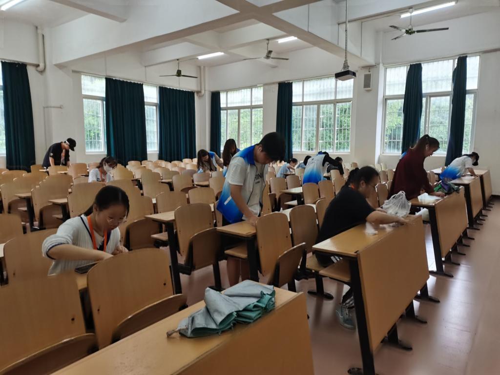图为志愿者们正在清洁教室桌椅